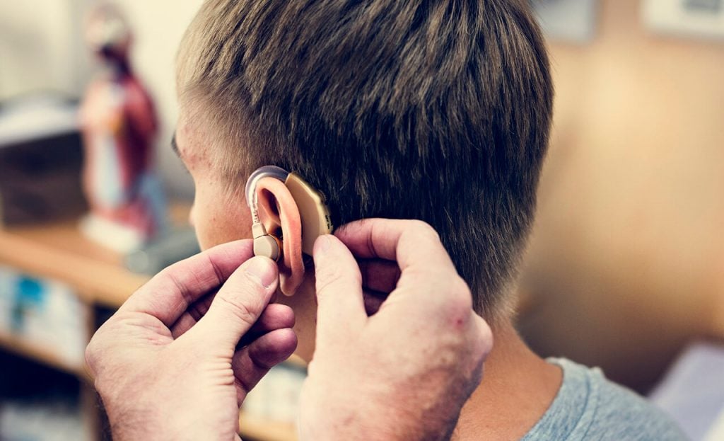 A man having his ears checked and hearing aid fitted