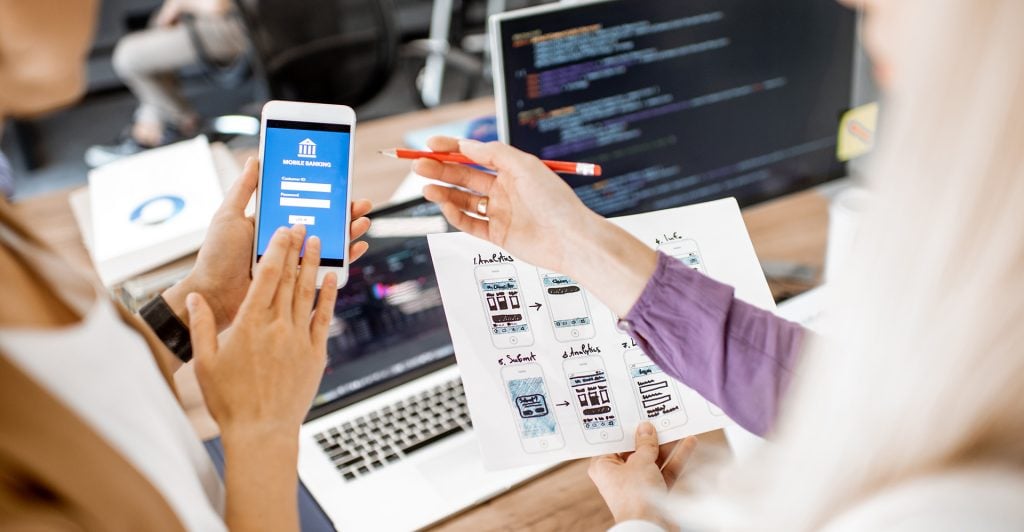 two persons gesturing to a mobile device with a form design