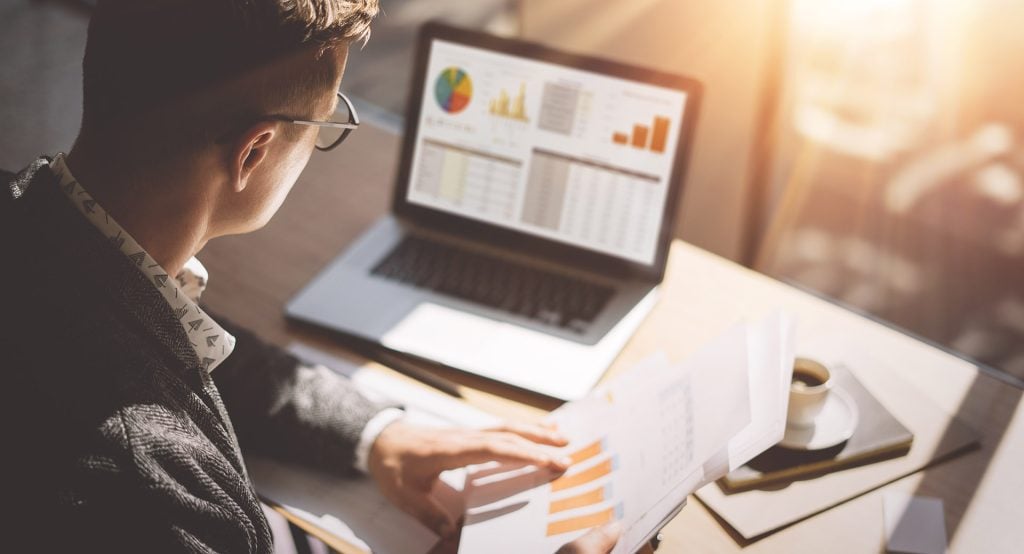 Investment manager at a workstation examining a fund factsheet