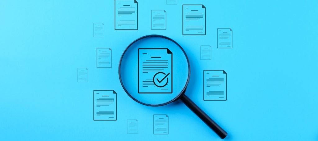 Magnifying glass hovering over a report icon with a checkmark